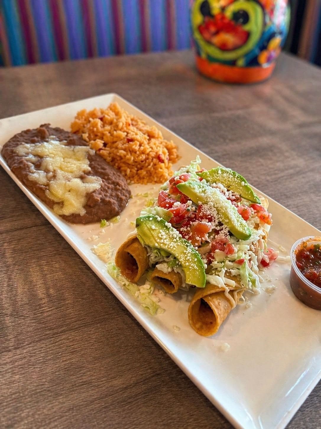 Two rolled one folded taco dinner with rice, beans, avocado, and salsa