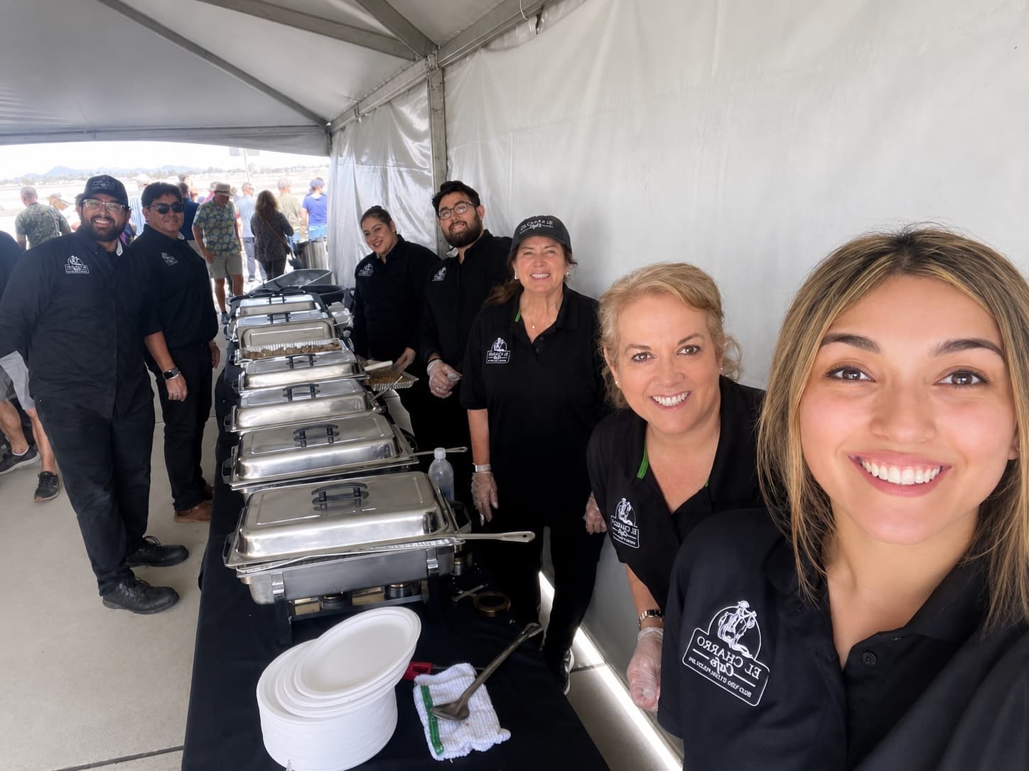 El Charro catering team smiling beside a buffet service line