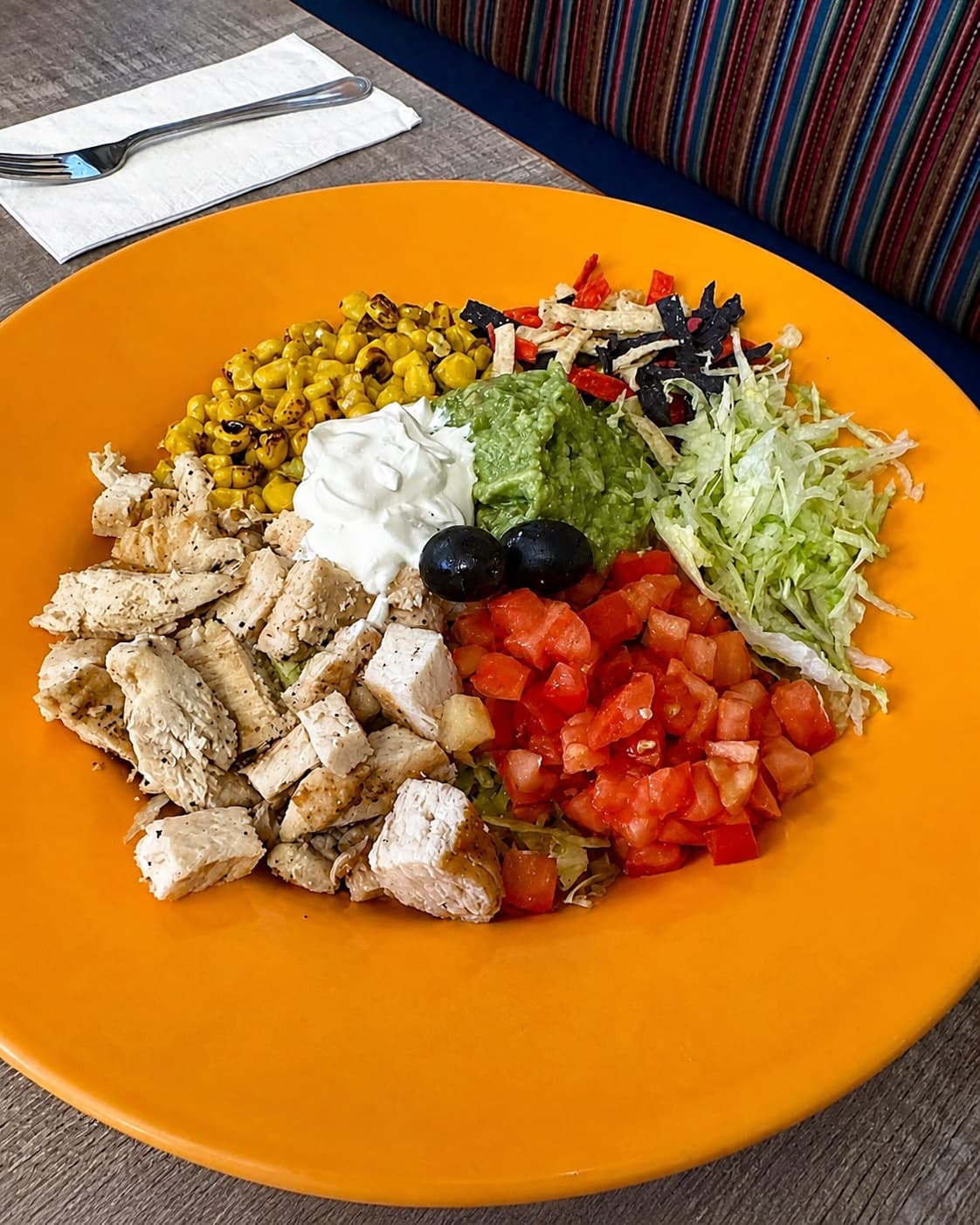 Chicken salad with guacamole, tomato, corn, lettuce, and sour cream