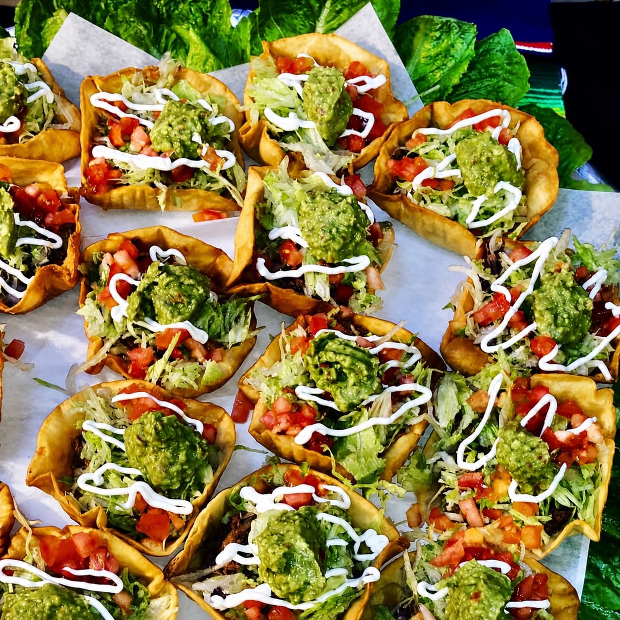 Crispy taco bowls topped with lettuce, tomato, sour cream, and guacamole