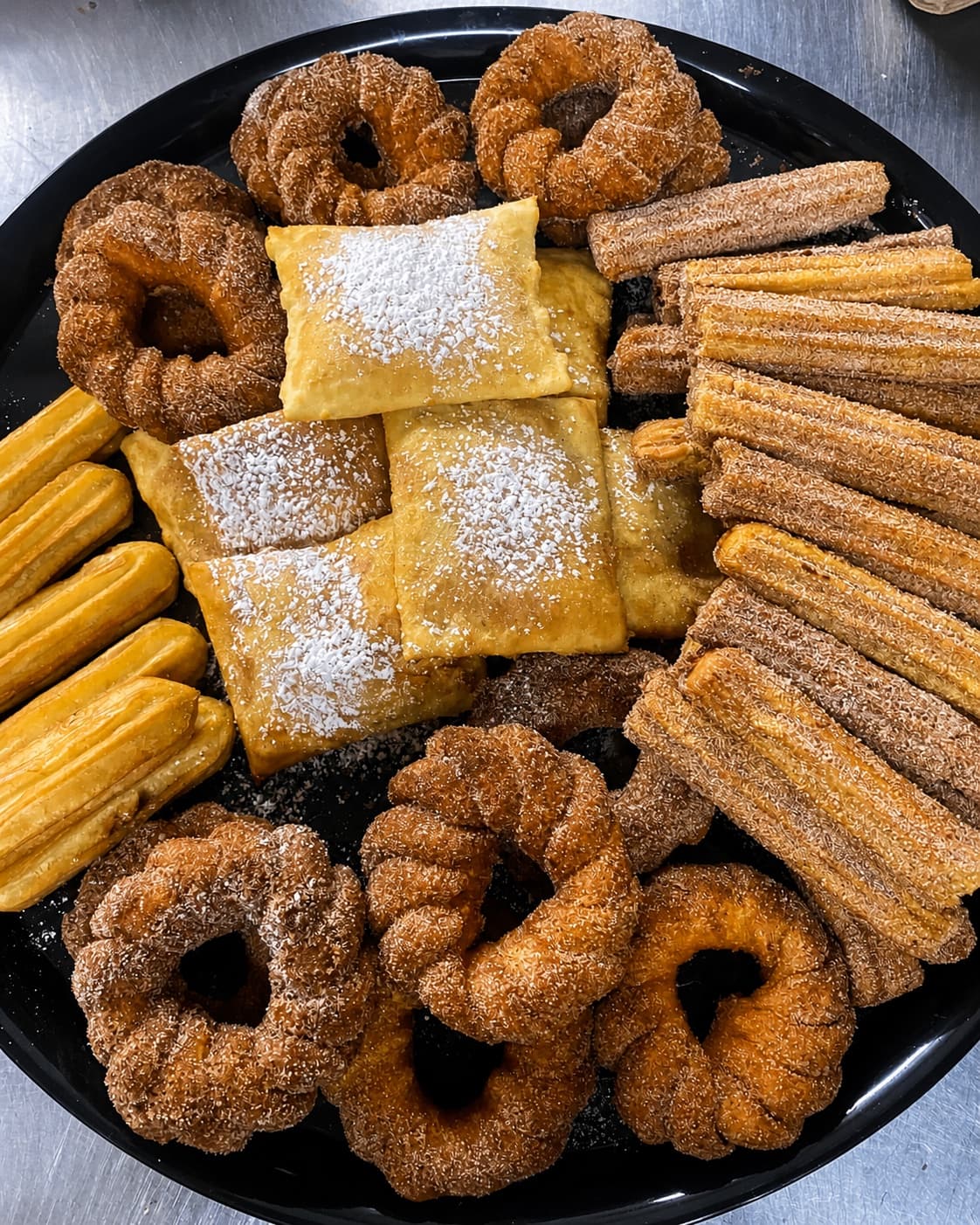 Dessert party tray with churros, pastries, and powdered sugar