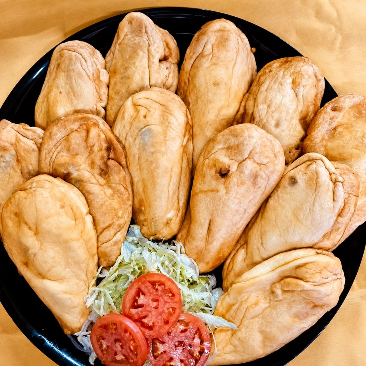 Party tray filled with empanadas and garnished with lettuce and tomato