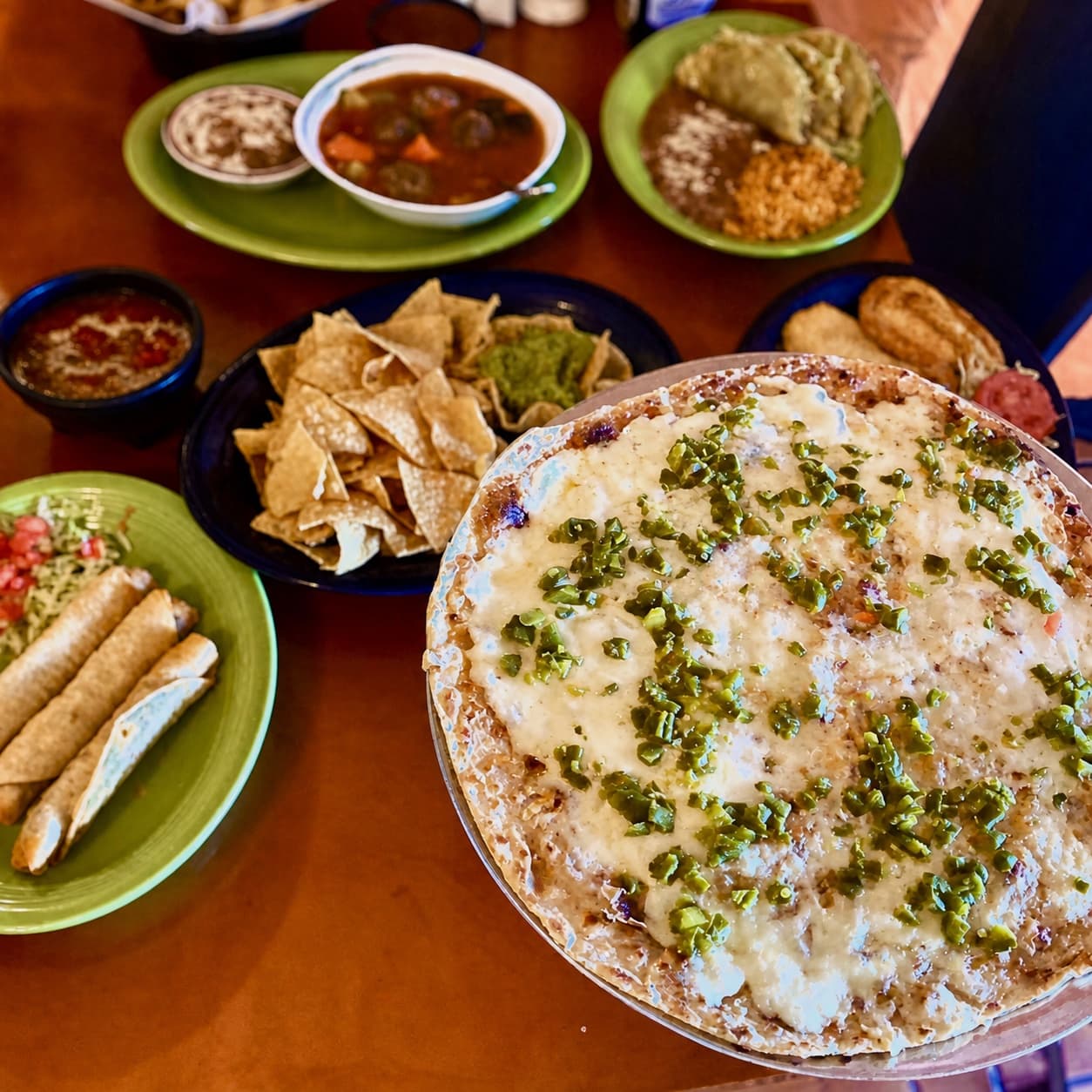 El Charro table spread with Green Saddle, chips, salsa, soup, tacos, rice, and beans