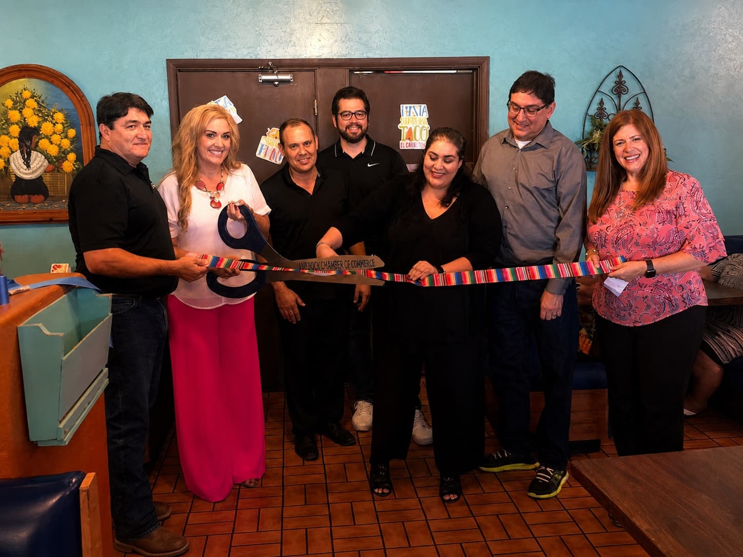 Group holding a ribbon during an El Charro community celebration